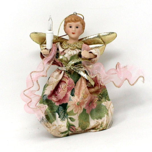 A vintage porcelain and fabric lighted angel ornament with gold wings, holding a light, and dressed in a floral brocade gown with a pink tulle sash.