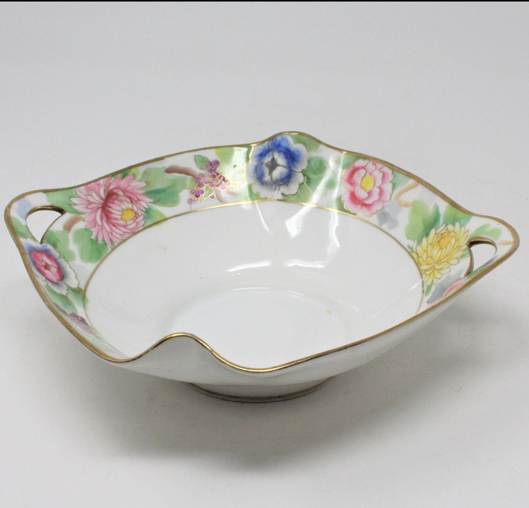 Antique hand painted porcelain bowl with floral patterns and gold accents, featuring built-in double handles.