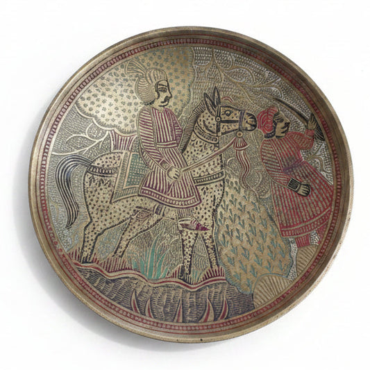 A decorative brass plate featuring a hand-carved design of a soldier on horseback with another figure on foot with a sword, detailed with colors red, black, and green.