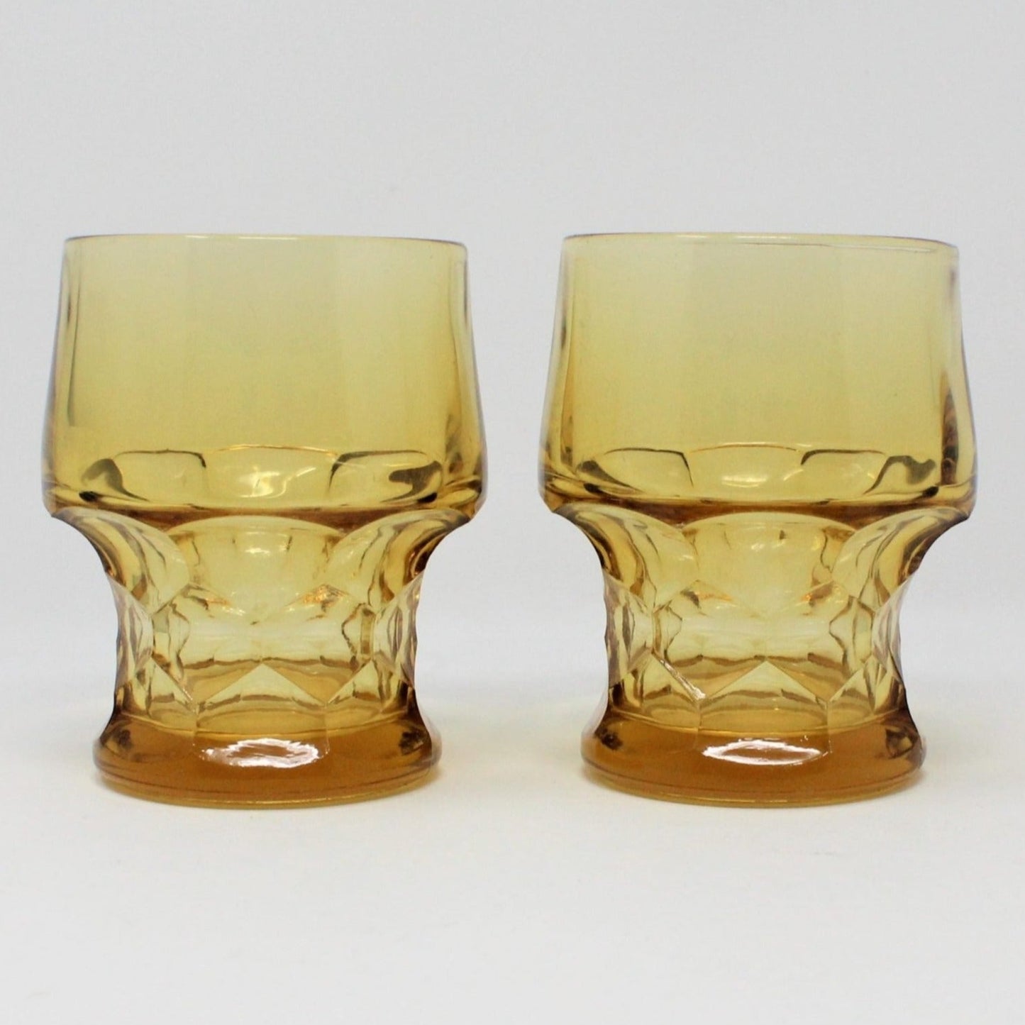 A pair of vintage amber-colored glass tumblers with a honeycomb pattern.