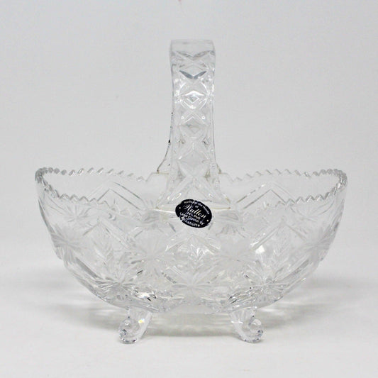 A clear lead crystal basket with a floral pattern, featuring a curved handle and resting on a flat surface.
