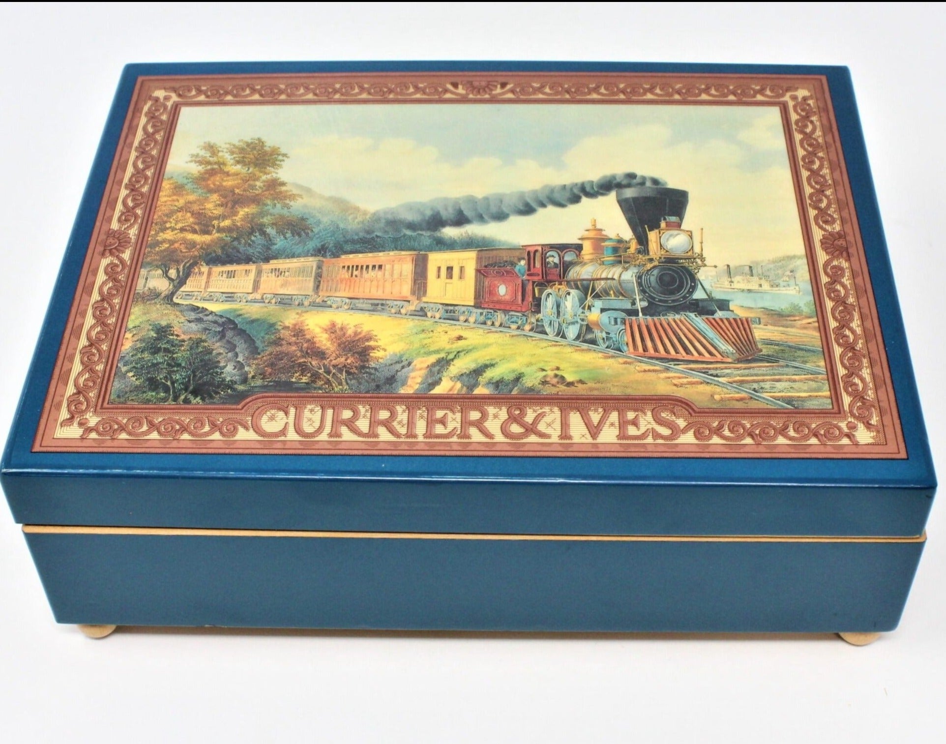 Vintage Enesco musical jewelry box with a Currier & Ives train design, blue lacquer, and velvet lining.