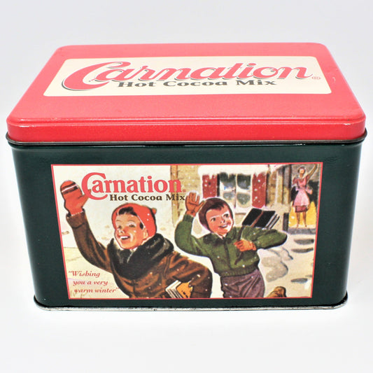 A vintage Carnation Hot Cocoa Mix tin with a red lid and a black base, featuring graphic illustrations of people on the side.