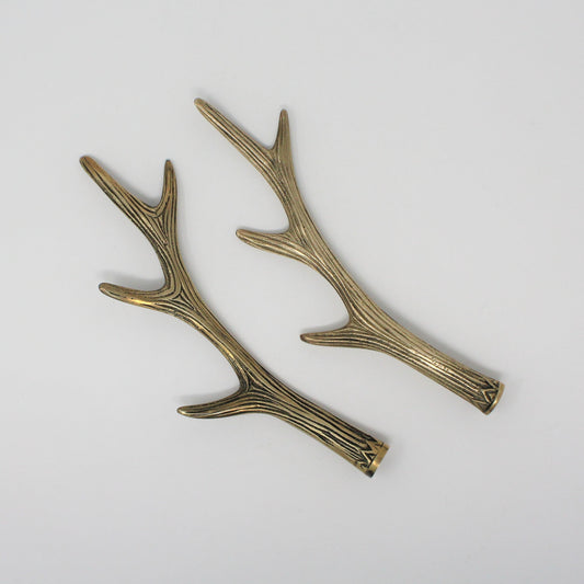 A pair of vintage brass hooks designed to resemble deer antlers, with a textured finish and patina.