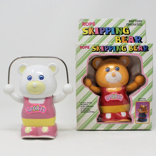 Vintage battery operated rope skipping bear toy in original packaging. The bear is white with a pink shirt, yellow shorts, and pink sneakers.
