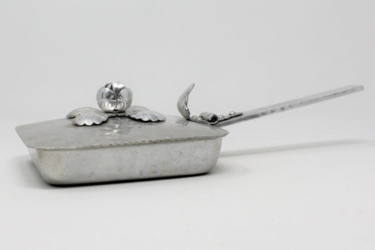Hammered aluminum silent butler with a rose bud design on the lid, side view showing the handle