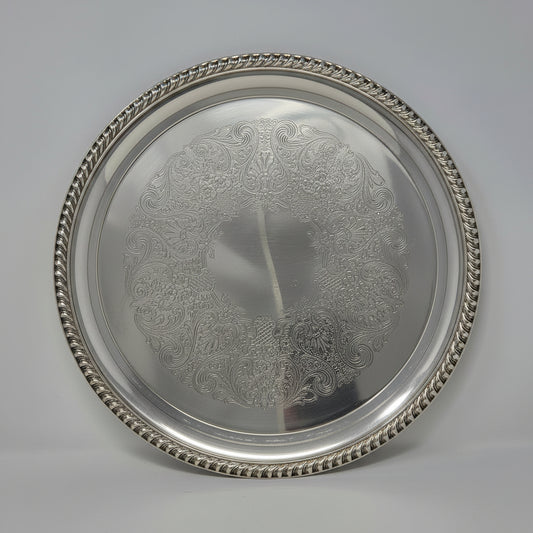 A vintage round silver serving platter with a decorative rope-textured rim