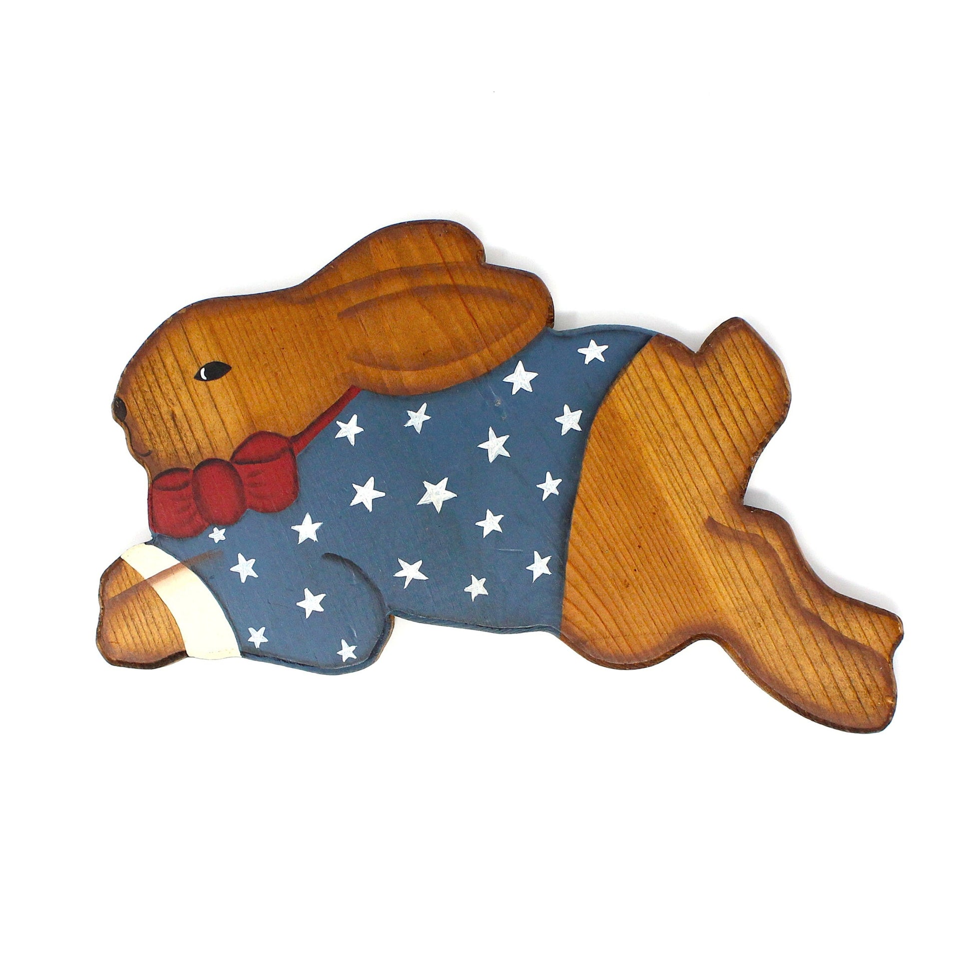 A wooden wall decor of a patriotic bunny rabbit with a stars and stripes pattern. He's classic Americana, wearing a red bow, in red, white, and blue colors.