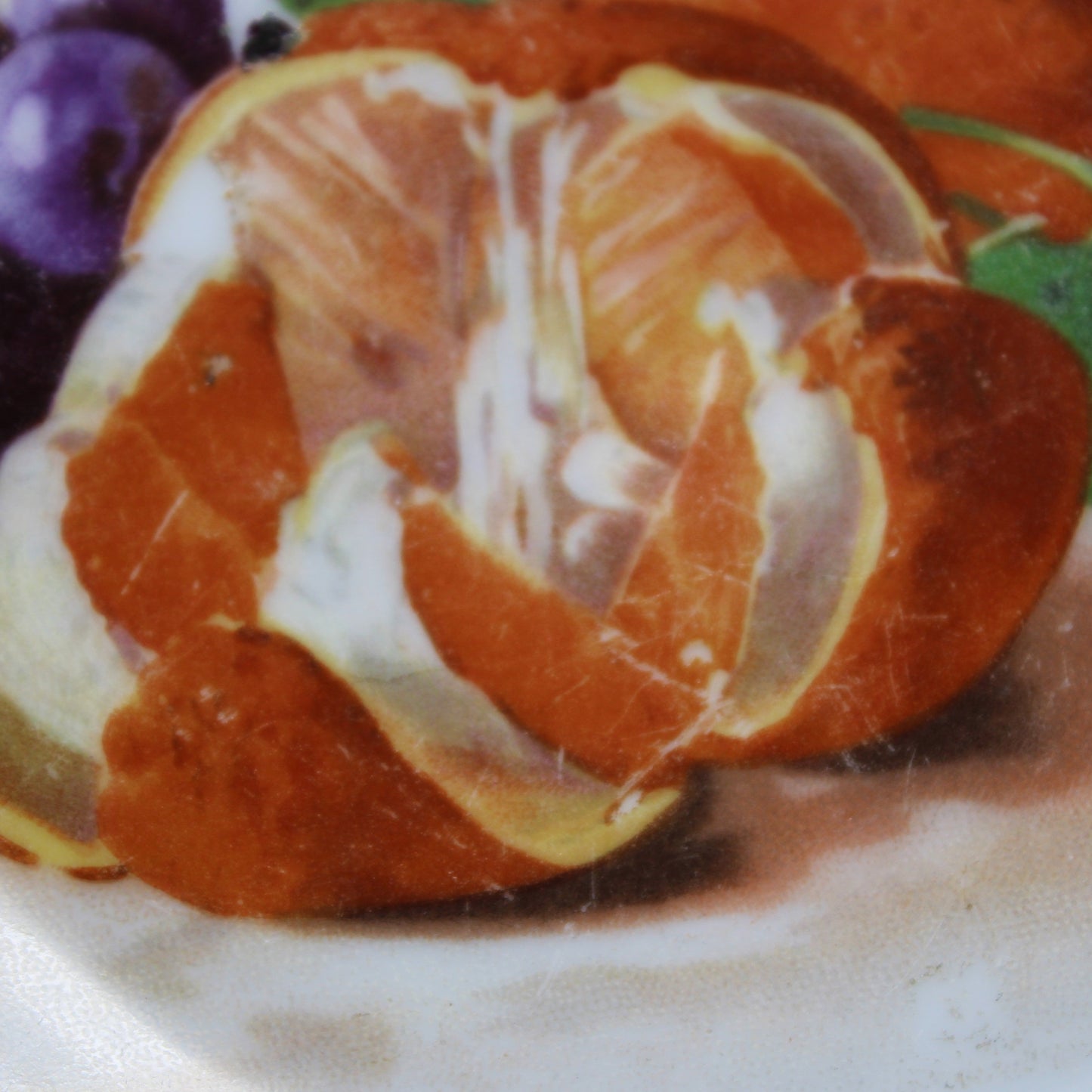 Close-up of a sliced orange on a decorative plate with grapes and figs.