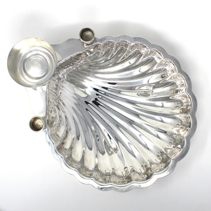 Top view of a silver shell-shaped serving dish with sauce bowl and candle holders.
