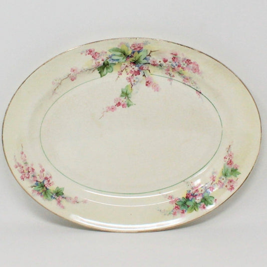 A vintage ceramic platter with a pink, blue, and green floral pattern and a gold rim, made in USA by Pope Gosser pottery.