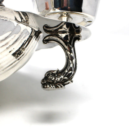 Up-close view of dolphin shaped foot on silverplated clamshell bowl