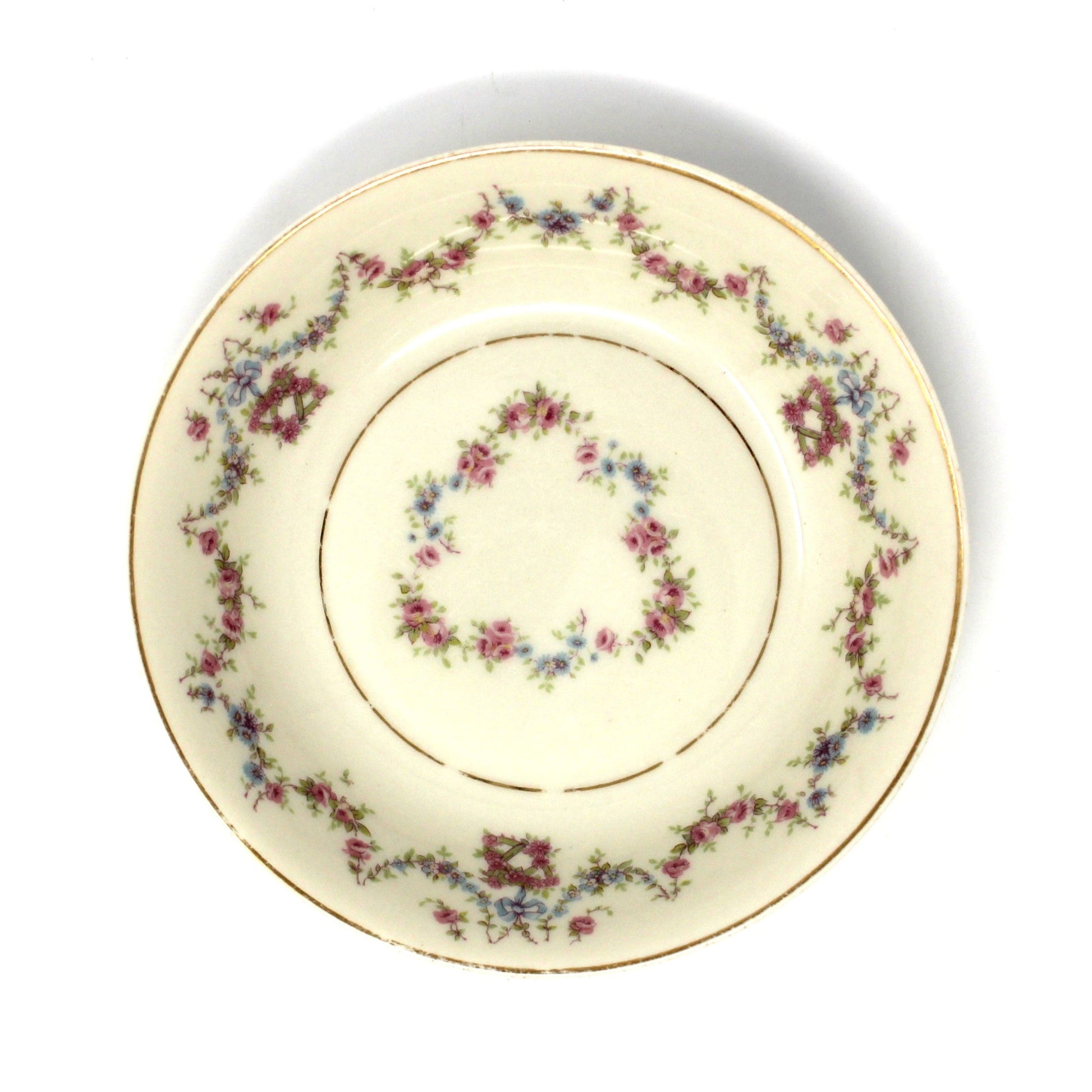 Decorative ceramic plate with pink and blue floral pattern on a beige background