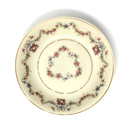 Decorative ceramic plate with pink and blue floral pattern on a beige background