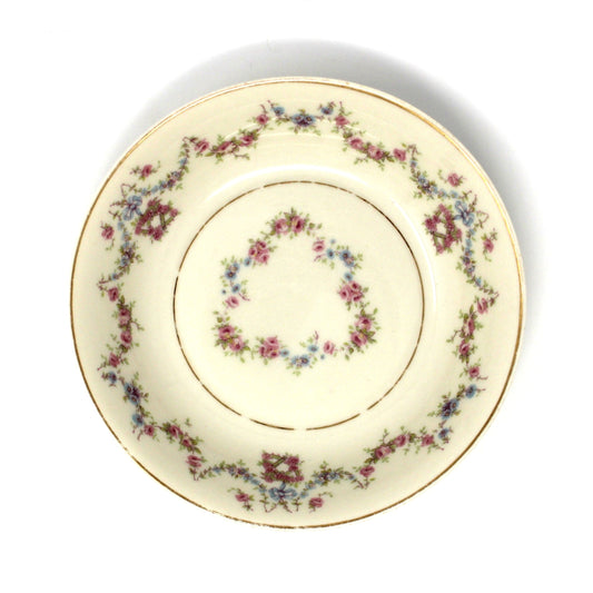 Decorative ceramic plate with pink and blue floral pattern on a beige background