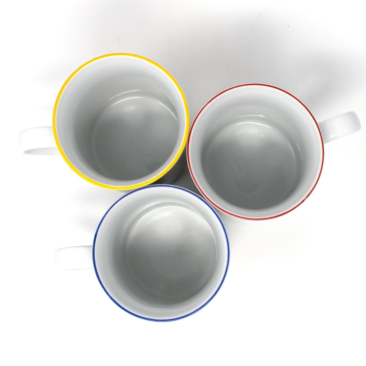 Three ceramic cups with colorful rims on a white background