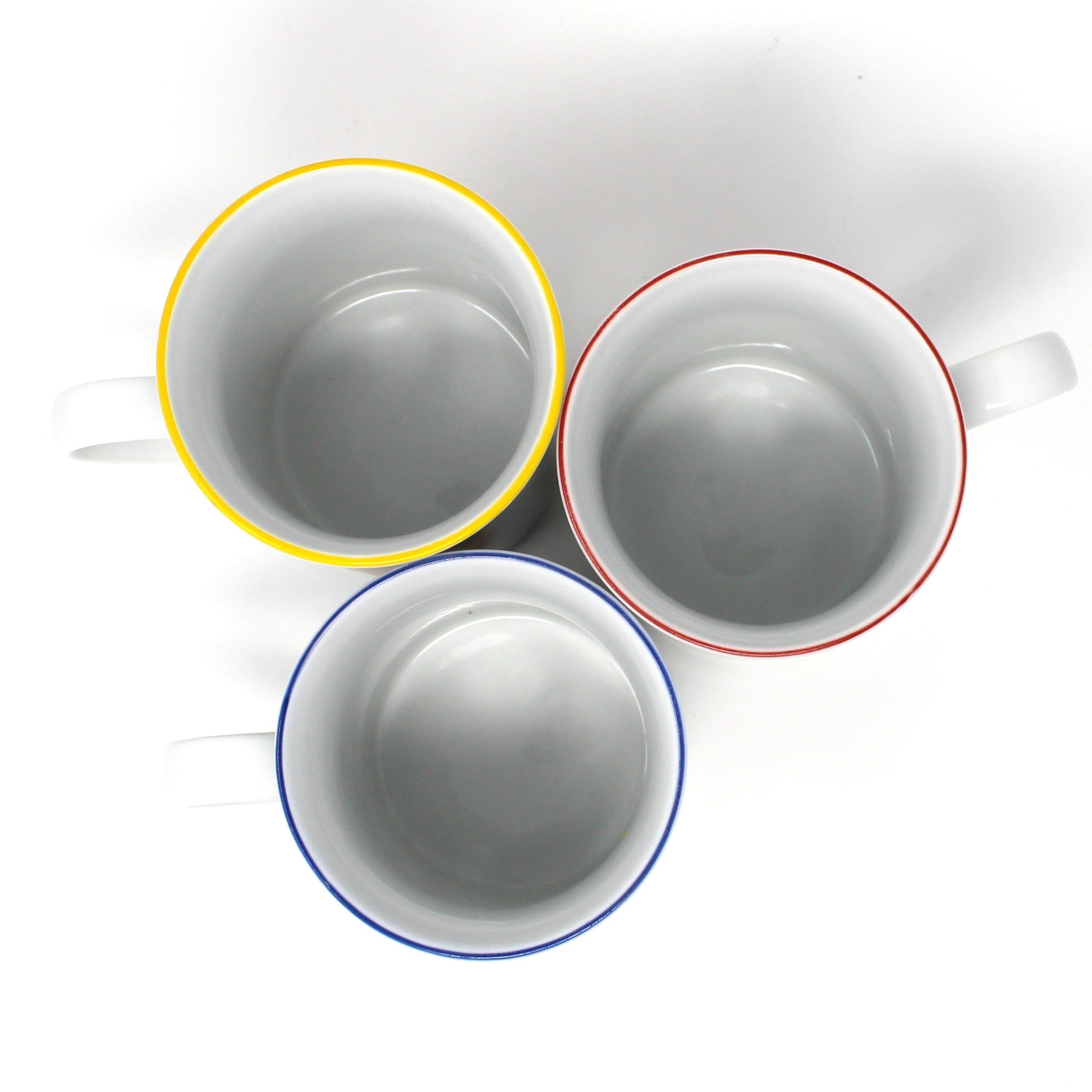 Three ceramic cups with colorful rims on a white background
