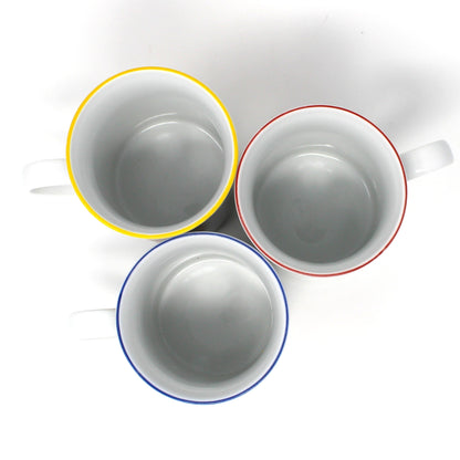 Three ceramic cups with colorful rims on a white background