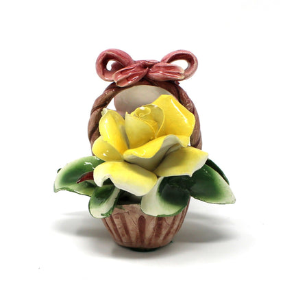 Small figurine of a girl with a yellow flower on a white background