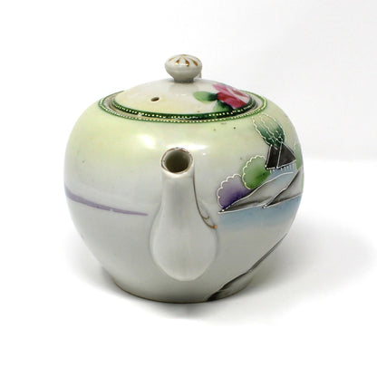 Ceramic teapot with floral design on a white background