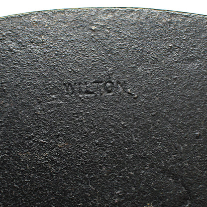 Close-up of a black cast iron bookend with 'Wilton' branding 