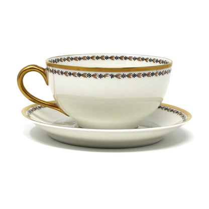 Antique porcelain teacup and saucer by Haviland & Co, Limoges. With decorative trim, gold laurel leaves and black flowers.