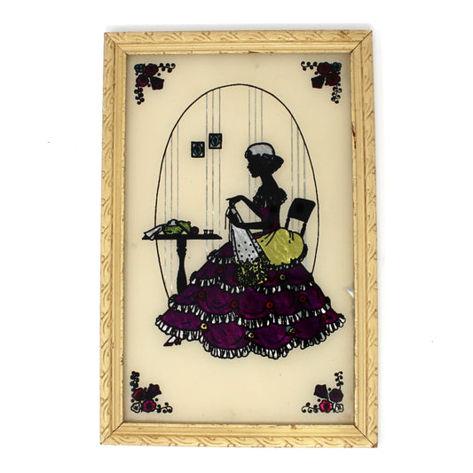Vintage Decorative wall art with a framed silhouette of a Victorian woman sewing with color foil on dress 