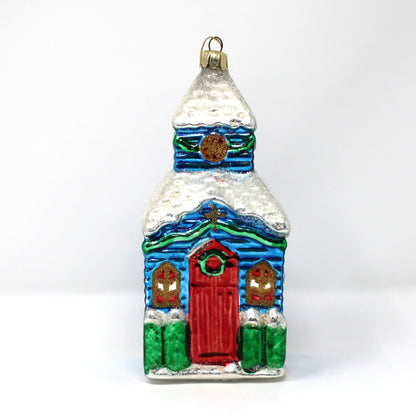 Vintage blown glass ornament of a church with a red door,  snow covered steeple and lots of glitter.