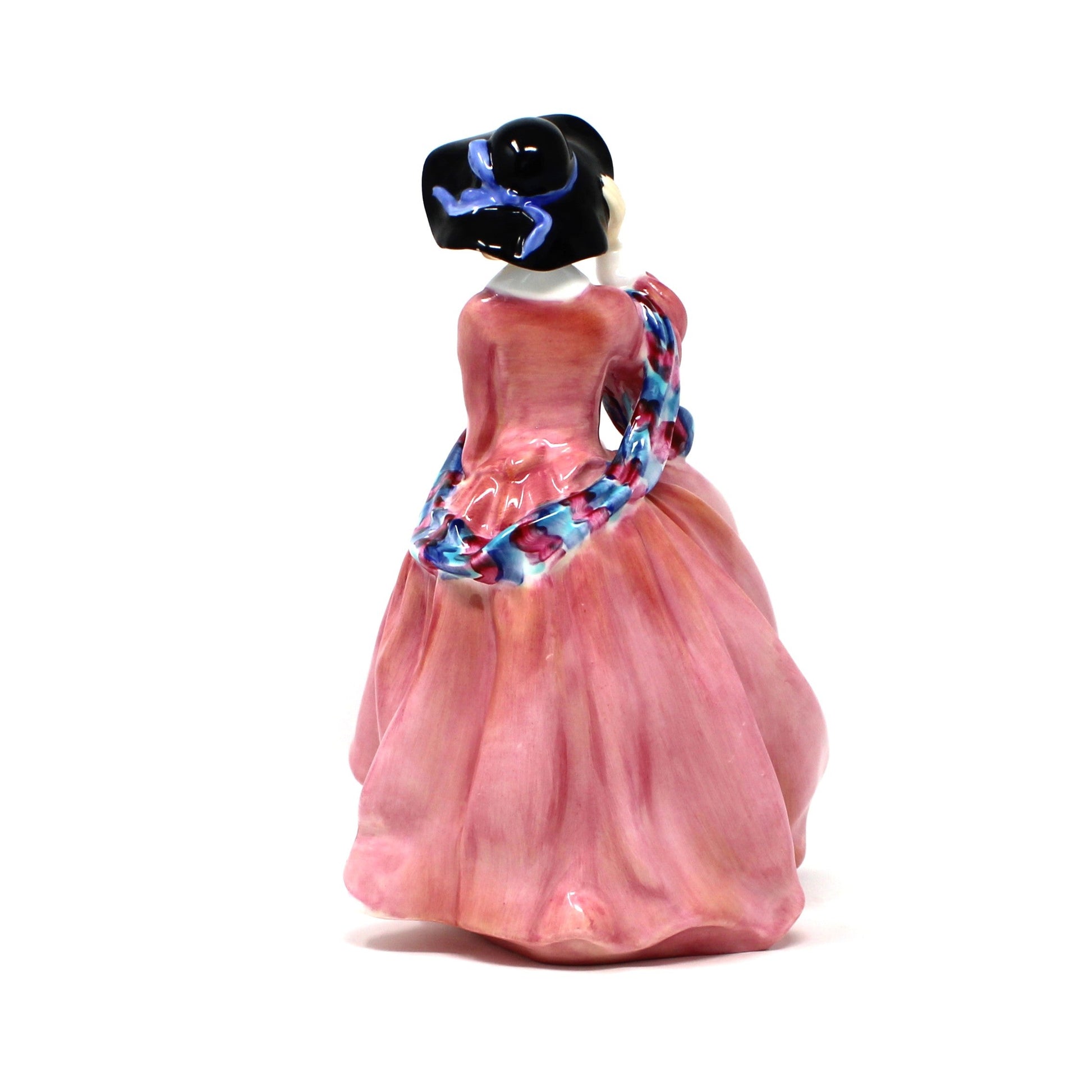 back view of vintage porcelain Royal Doulton figurine titled "Top O' The Hill". HN1849, of a woman in a flowing pink dress with blue hat.