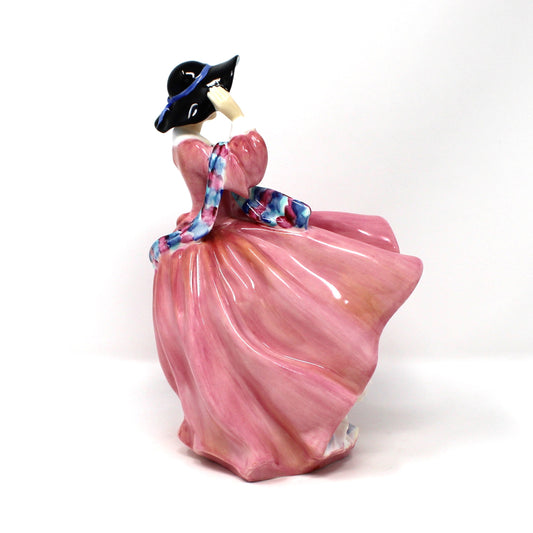 Right side view of vintage porcelain Royal Doulton figurine titled "Top O' The Hill". HN1849, of a woman in a flowing pink dress with blue hat.