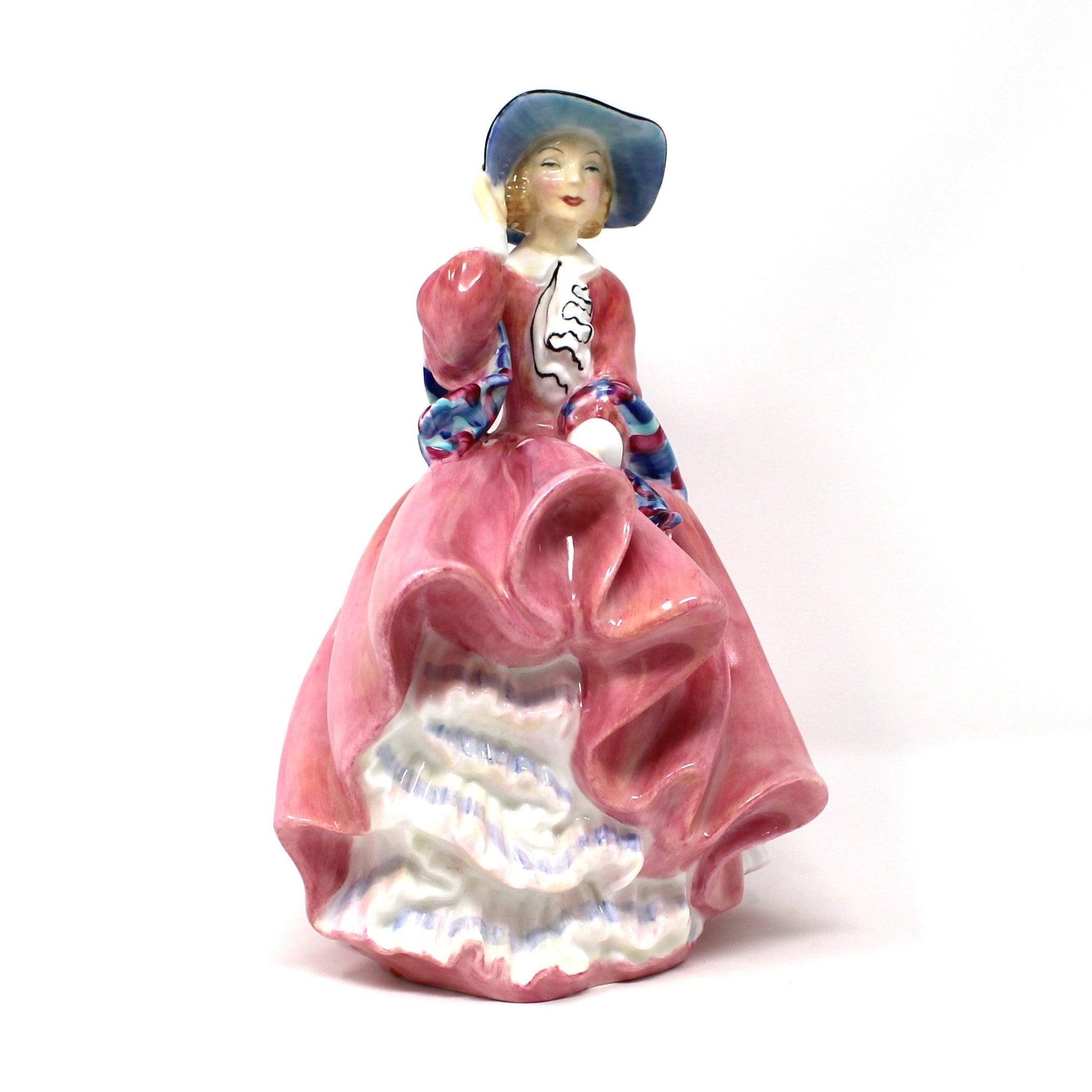 Front view of vintage porcelain Royal Doulton figurine titled "Top O' The Hill". HN1849, of a woman in a flowing pink dress with blue hat.