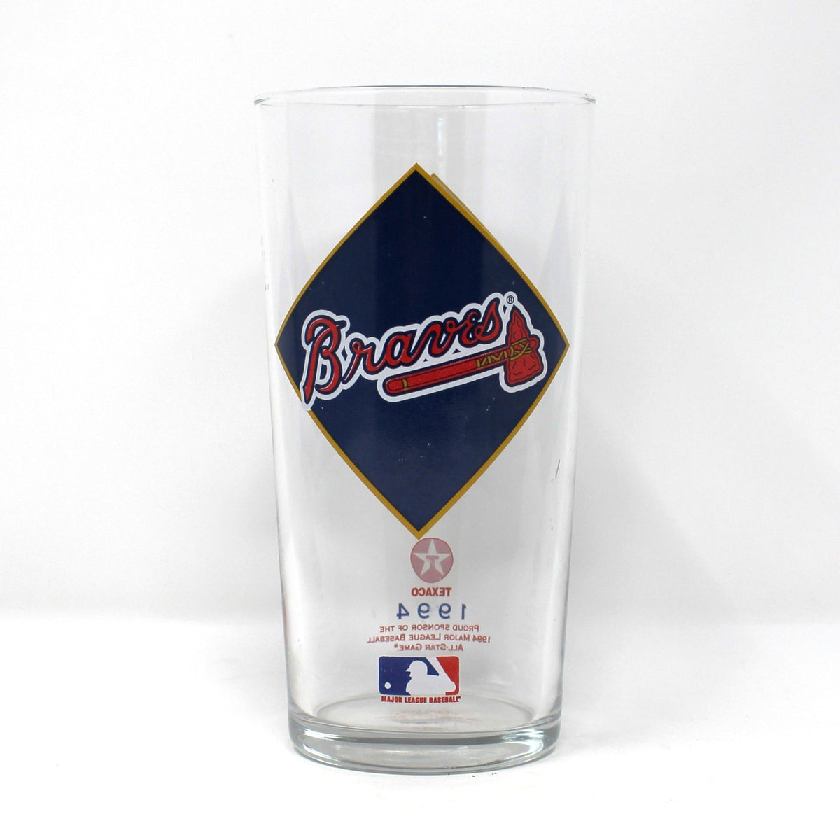 A vintage clear beer glass tumbler featuring a large navy blue diamond graphic with the Atlanta Braves logo in red and white, and a small MLB mark near the bottom. 1994