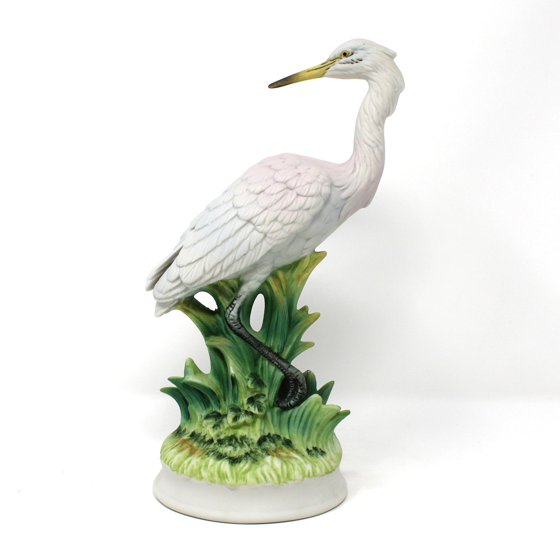 A vintage ceramic figurine of a white heron bird standing on green reeds, bisque porcelain.  Angeline Originals, Japan.