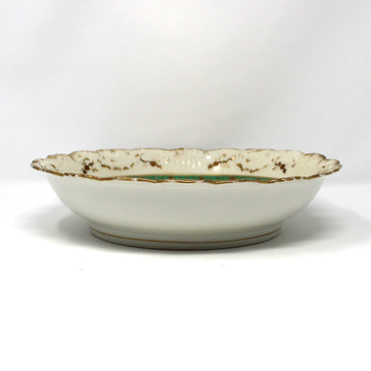 A Victorian cabinet porcelain bowl with a scalloped rim, featuring an off-white glaze, gold speckled detailing, and a thin green stripe near the edge.