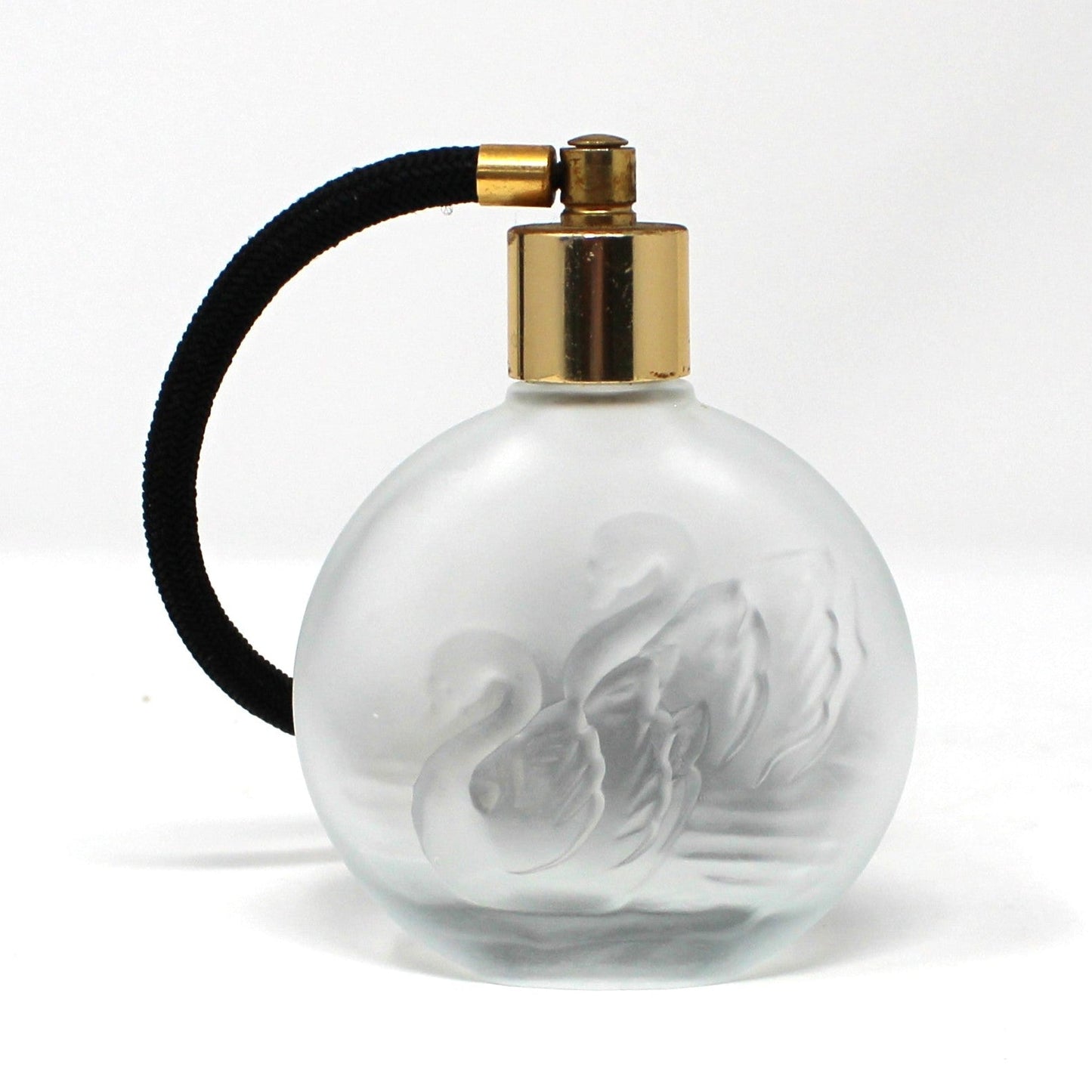 A vintage round frosted glass perfume bottle with a gold spray nozzle and a black atomizer