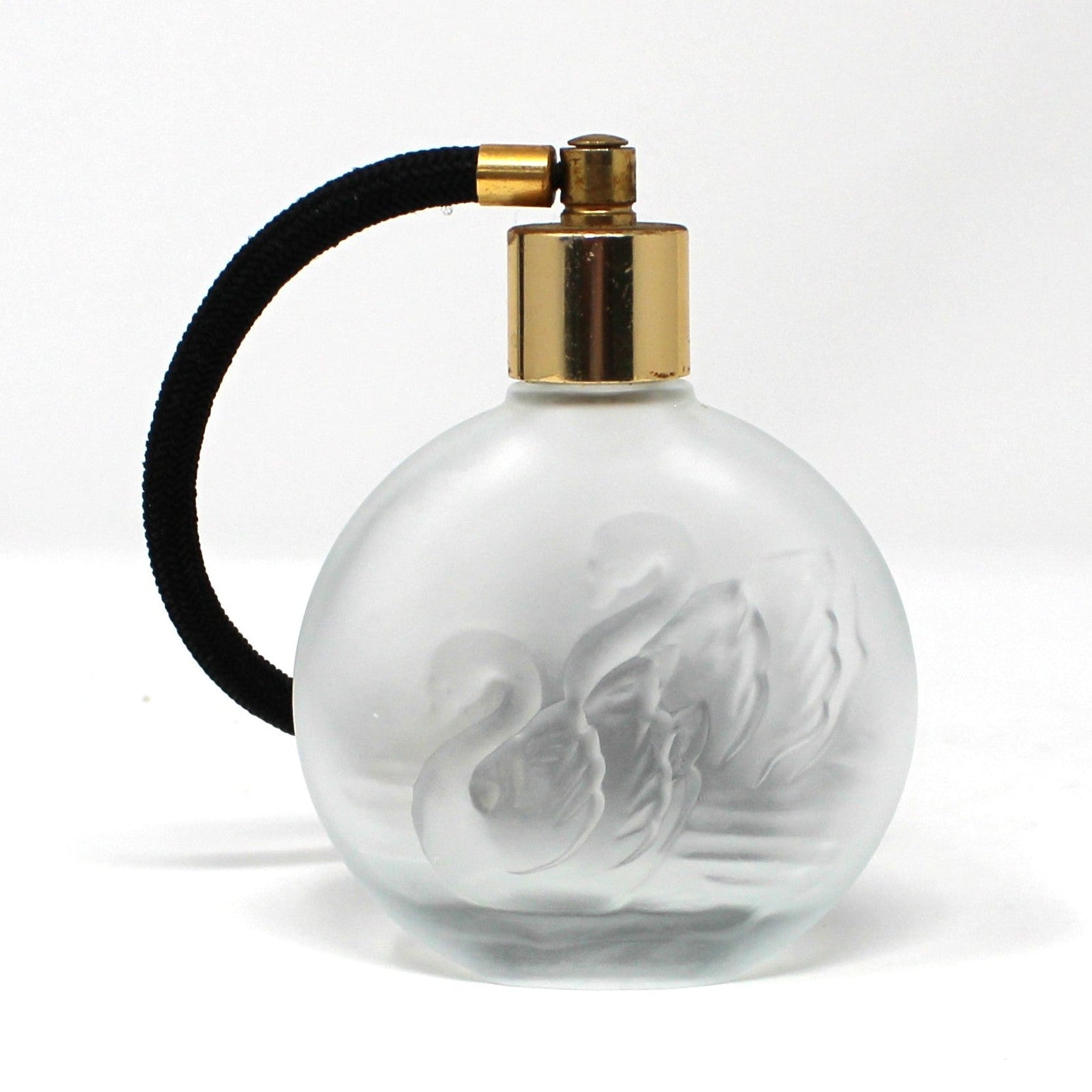 A vintage round frosted glass perfume bottle with a gold spray nozzle and a black atomizer