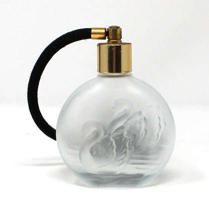 A vintage round frosted glass perfume bottle with a gold spray nozzle and a black atomizer
