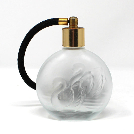 A vintage round frosted glass perfume bottle with a gold spray nozzle and a black atomizer