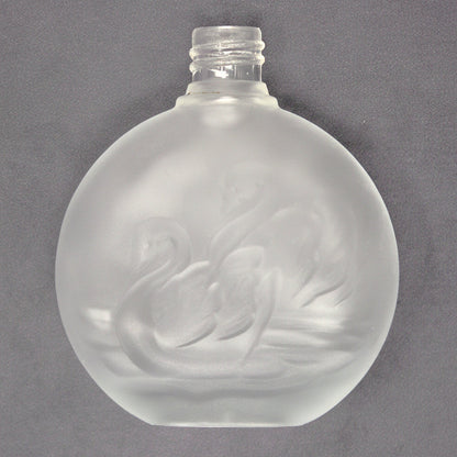 A vintage perfume bottle, clear frosted glass with a double swan motif embossed on the front