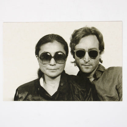 A vintage postcard, John Lennon and Yoko Ono in a black and white photograph wearing sunglasses. Photo by David Spindel
