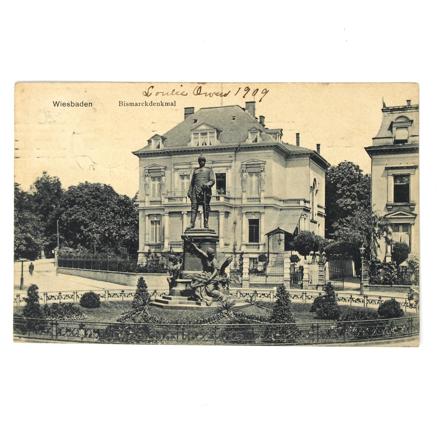 Antique black and white postcard depicting a grand neoclassical building with a central statue and manicured gardens. Travel postcard, Germany