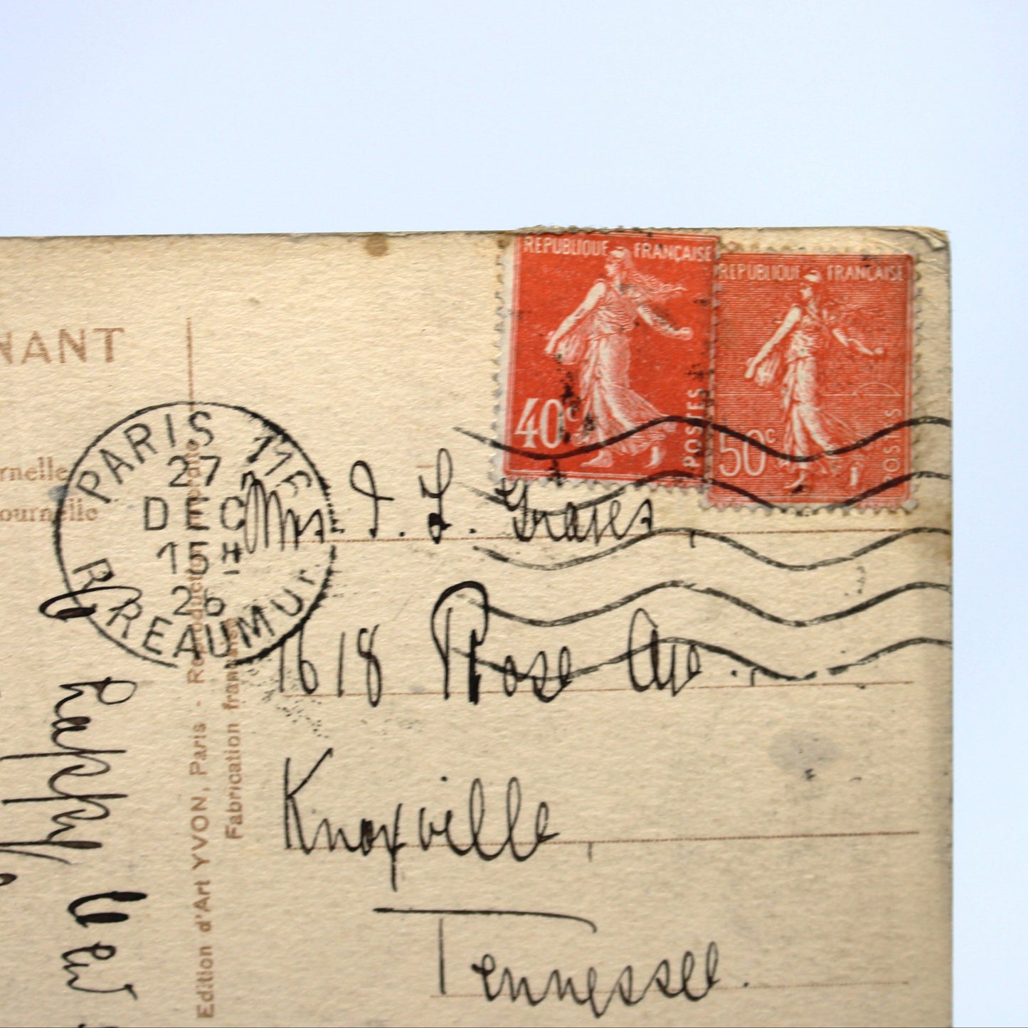 Vintage French postcard with two red 40-cent stamps, handwritten address in Nancy, Tennessee, and a circular Paris postmark, shown against a light blue background.