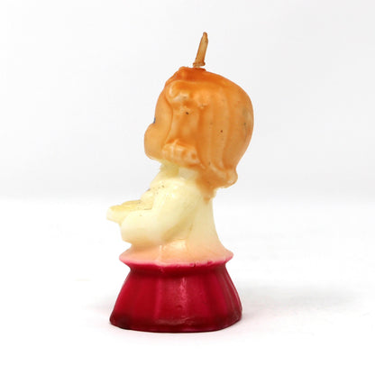 Side view of a vintage Gurley novelty candle shaped like a caroling girl with a white and red dress.