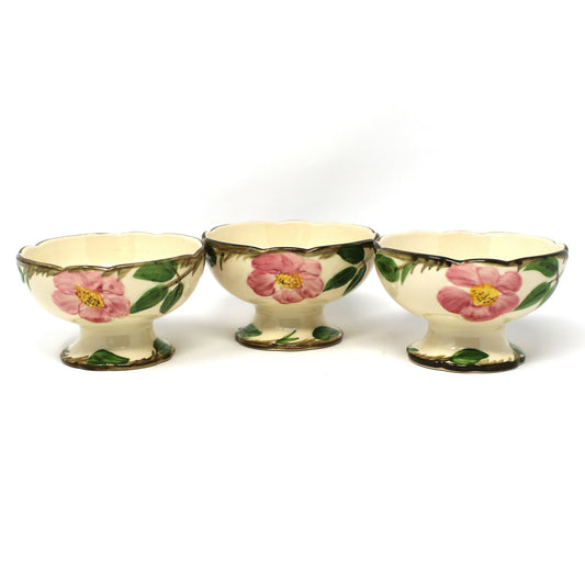 Three vintage Franciscan Desert Rose  footed bowls with a cream background and pink floral designs with green leaves.