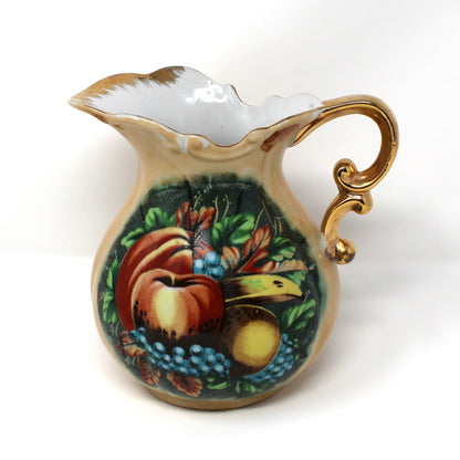 A view of the pitcher from a vintage Enesco ceramic pitcher and basin set with hand-painted fruit motifs, including red apples, yellow pears, and blue grapes.