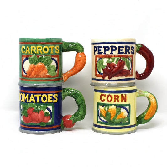 Four ceramic vegetable-themed mugs  The mugs are labeled Carrots, Peppers, Tomatoes, and Corn with colorful illustrations of the vegetables and vegetable handles.