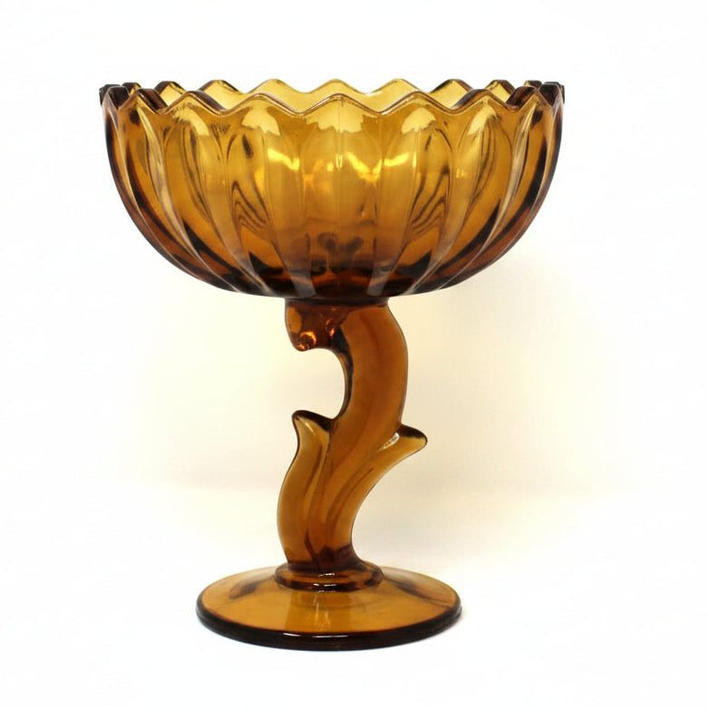 A vintage amber glass pedestal bowl from Indiana Glass.  Lotus Blossom compote with a scalloped rim and a sculptural stem.