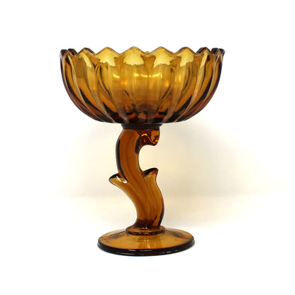 A vintage amber glass pedestal bowl from Indiana Glass.  Lotus Blossom compote with a scalloped rim and a sculptural stem.