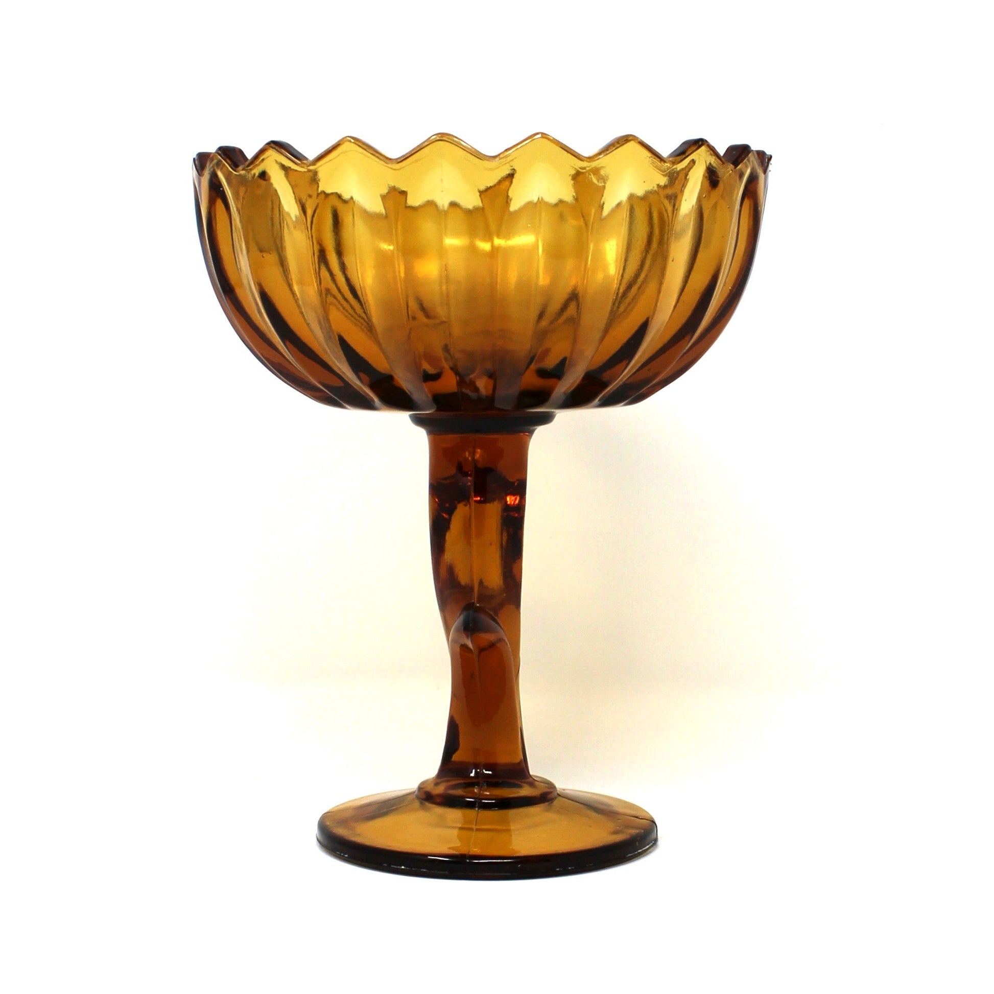 Side view of a vintage amber glass pedestal bowl from Indiana Glass.  Lotus Blossom compote with a scalloped rim and a sculptural stem.