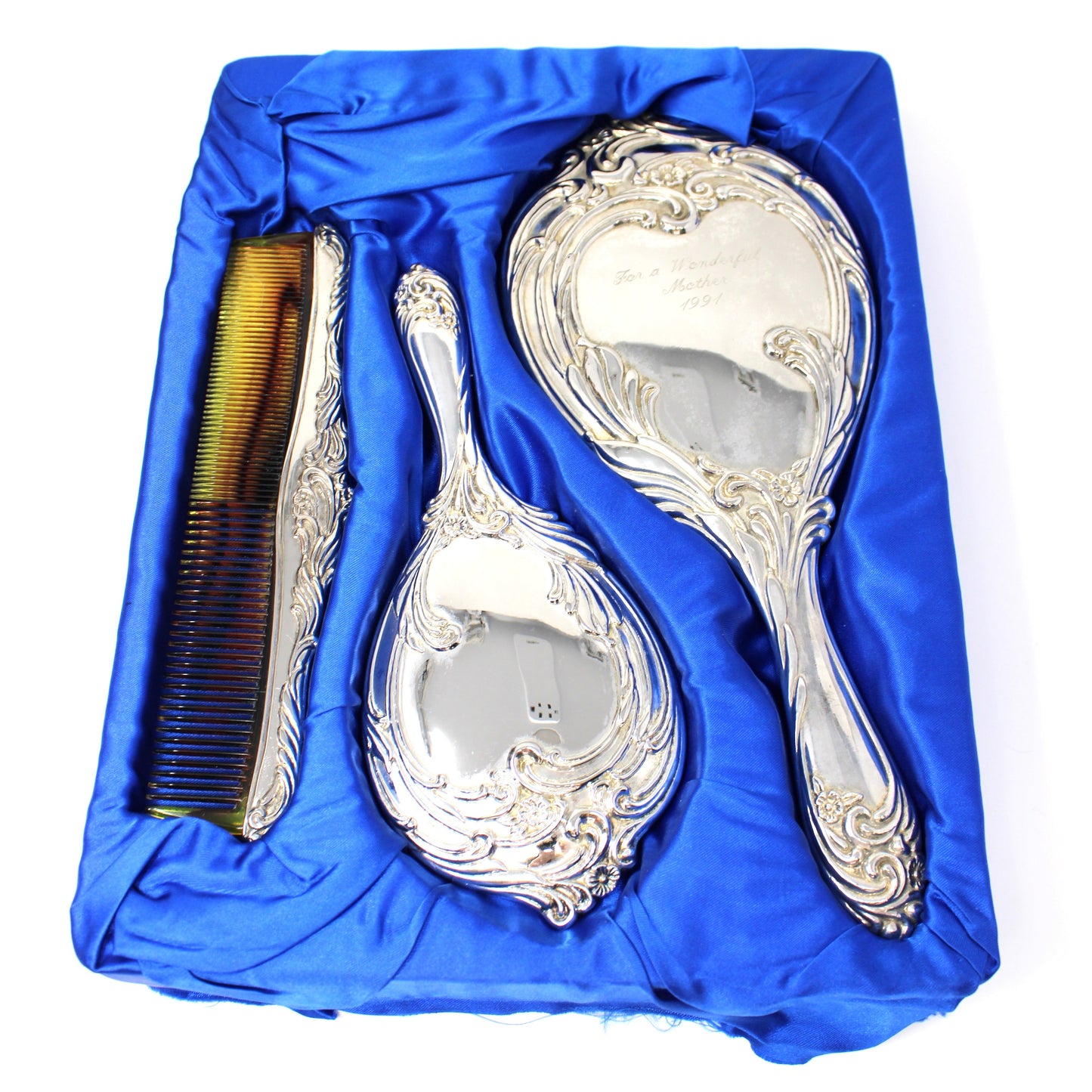 A vintage three-piece silver vanity set including a large hand mirror, a brush, and an ornate comb from ISC.
